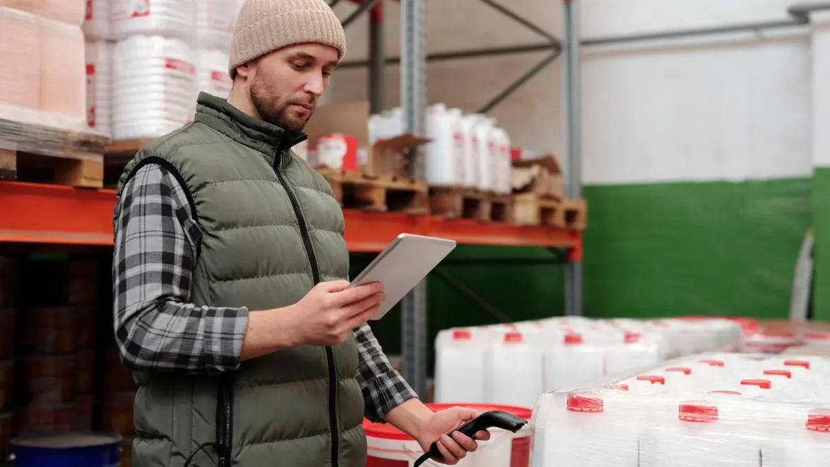 Préparateur de commande en entrepôt Amazon scannant des colis sur une ligne logistique lumineuse.